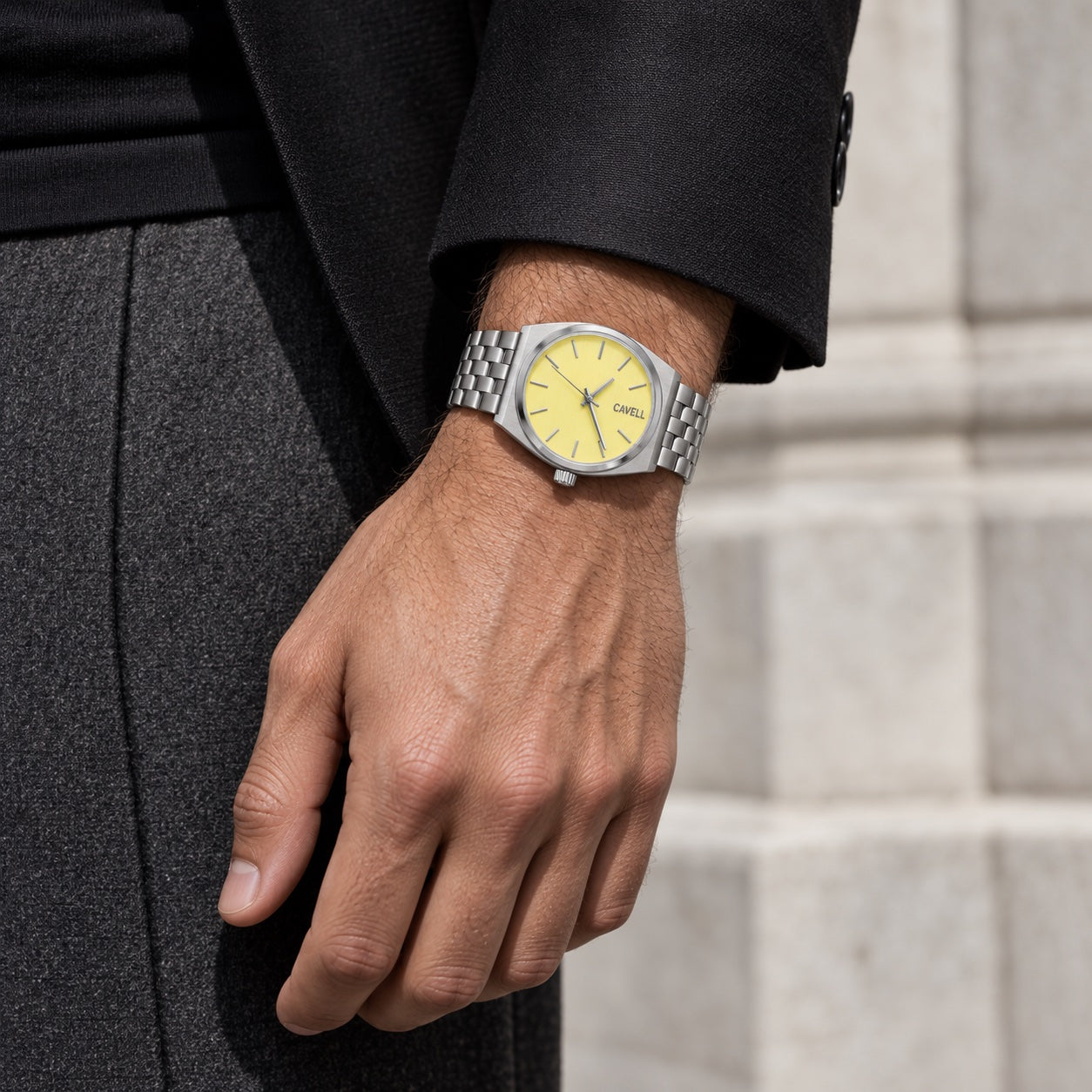 Silver and butter CAVELL watch on a man's wrist with black tailoring