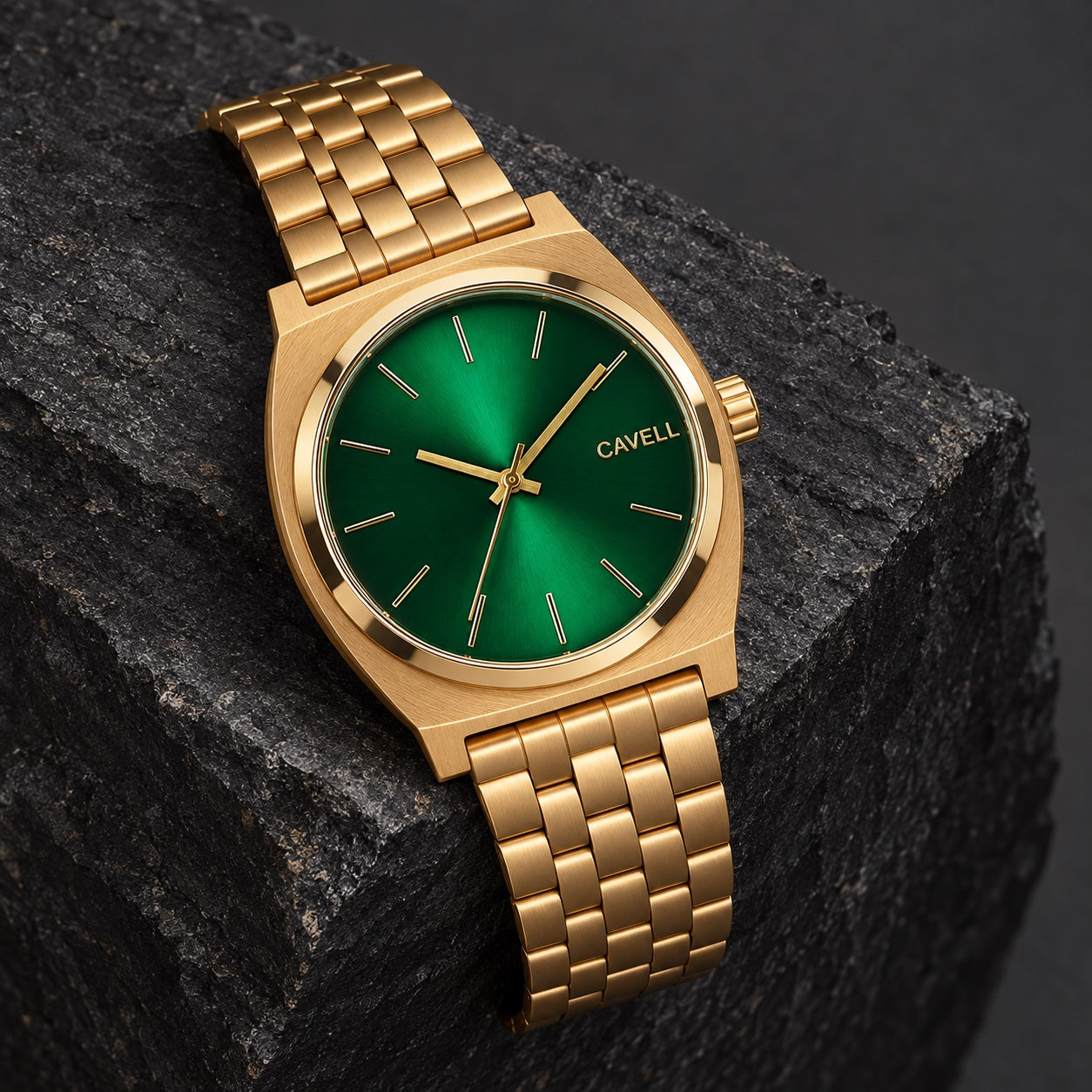 Gold CAVELL watch with a green sunray dial resting on dark slate